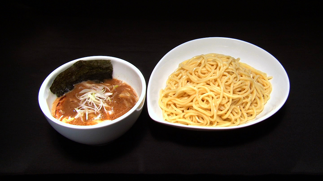 Azzurri の看板メニューは、癖になる不思議なおいしさの『つけ麺』！濃厚豚骨魚介スープにタピオカ配合のモチモチ麺が絡みまくって、一度食べたら忘れられないと大評判！そのおいしさに隠された、かなり珍しい秘密…それはつけ汁に使う “タレ” にあったんです！ラヲタの田中さんでさえ何の食材が使われているかわからない！と頭を抱えた謎のタレ。醤油ではないし、塩でもない、果たしてその正体とは！？